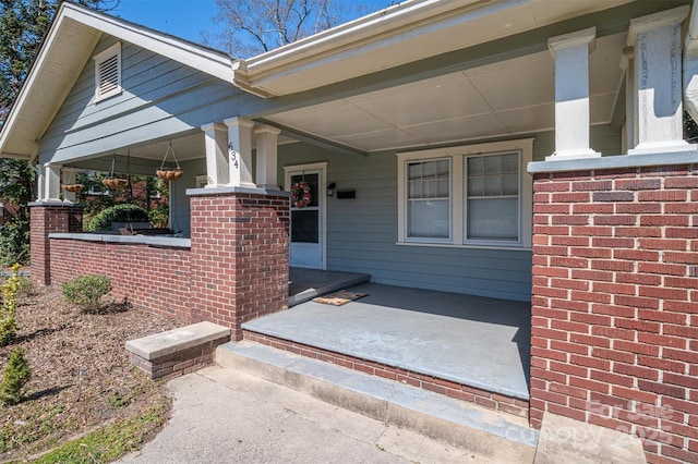 doorway to property with brick siding and a porch