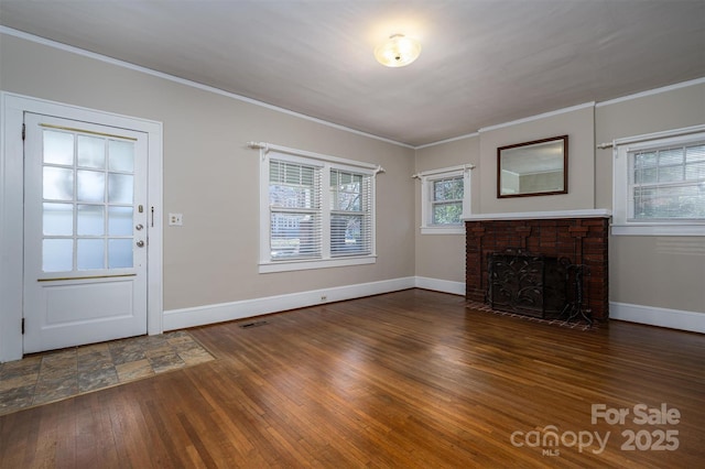 unfurnished living room with crown molding, hardwood / wood-style flooring, a fireplace, and baseboards