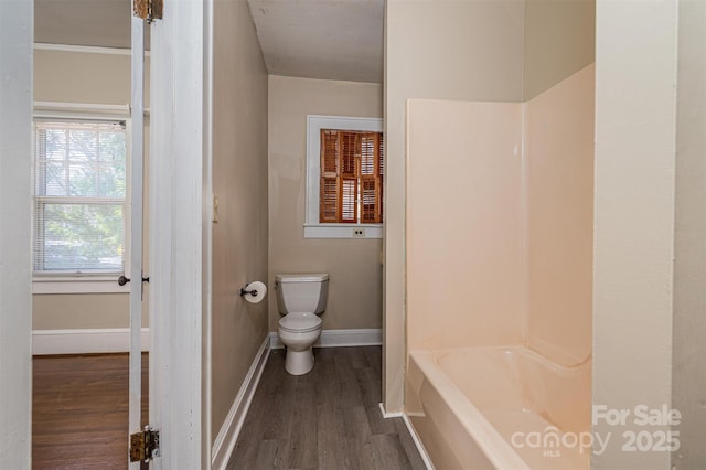 full bath with wood finished floors, baseboards, a tub to relax in, a shower, and toilet