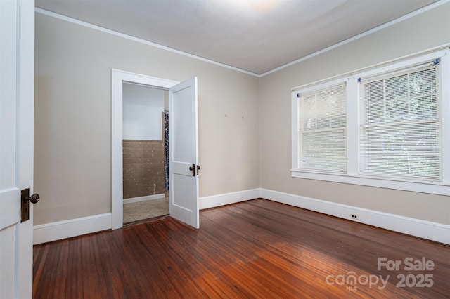 spare room with crown molding, hardwood / wood-style flooring, and baseboards