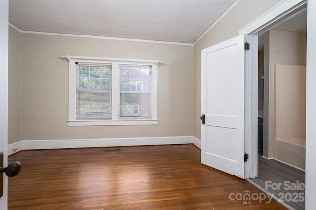 empty room with visible vents, baseboards, ornamental molding, and dark wood-style flooring