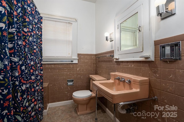 full bathroom featuring tile patterned flooring, curtained shower, toilet, tile walls, and a sink