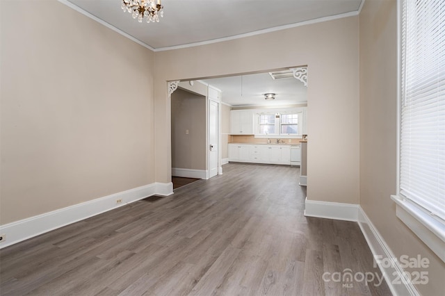 unfurnished living room with a chandelier, crown molding, baseboards, and dark wood-style flooring