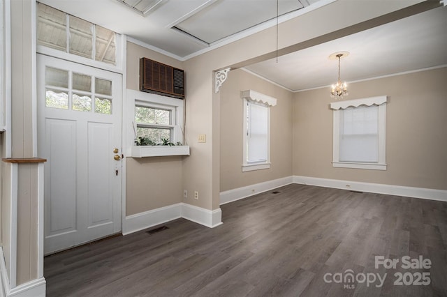 entrance foyer with visible vents, dark wood-type flooring, baseboards, ornamental molding, and a notable chandelier