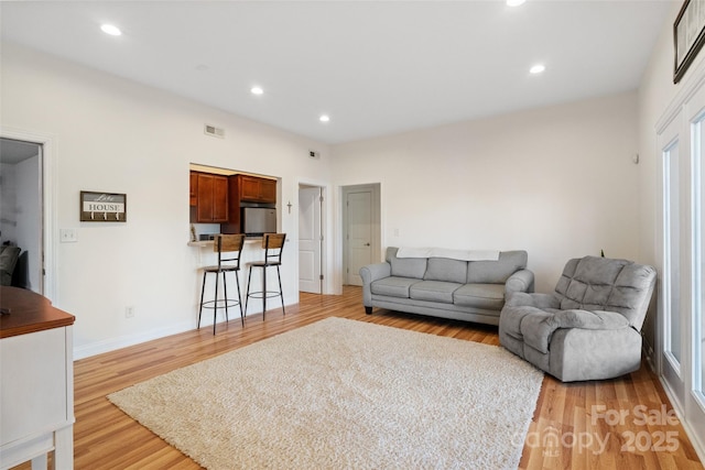 living area with recessed lighting, visible vents, baseboards, and light wood-style flooring