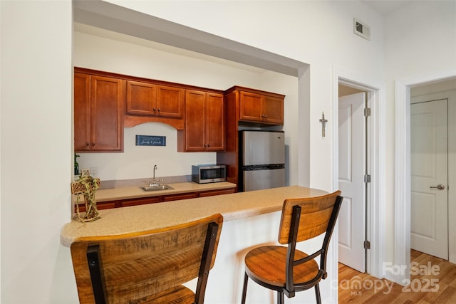 kitchen featuring visible vents, stainless steel appliances, a kitchen bar, and a sink