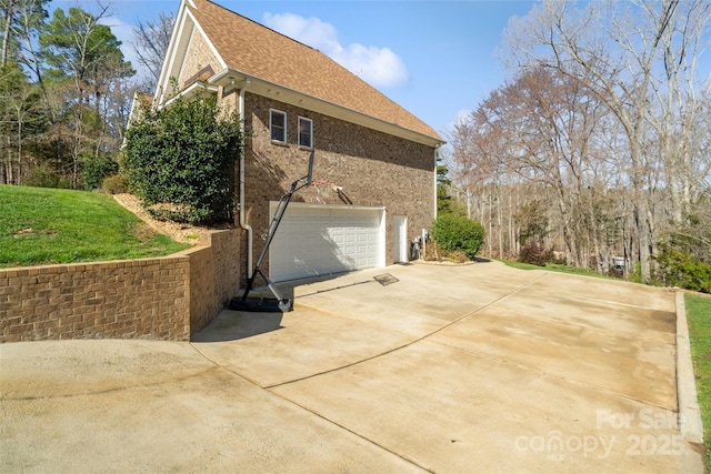 view of side of property with brick siding, concrete driveway, a garage, and roof with shingles