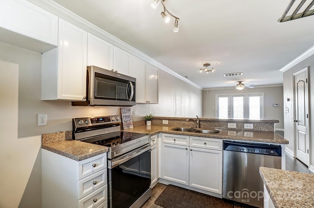 kitchen featuring visible vents, crown molding, appliances with stainless steel finishes, a peninsula, and a sink