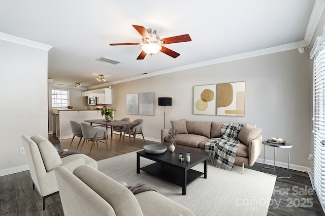 living area with visible vents, dark wood-style flooring, ornamental molding, and a ceiling fan
