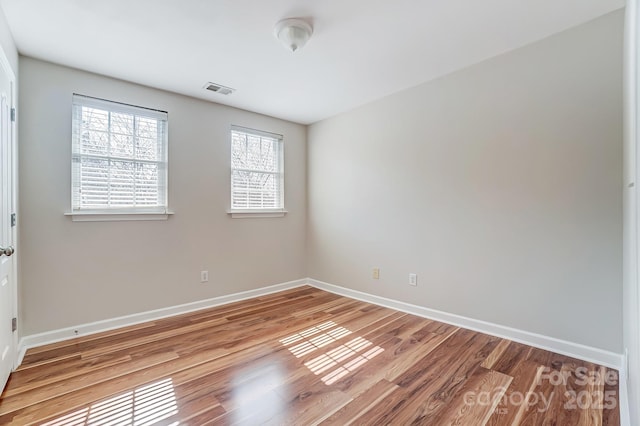 unfurnished room with visible vents, baseboards, and wood finished floors