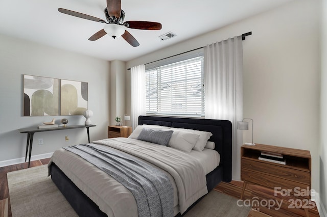 bedroom featuring ceiling fan, visible vents, baseboards, and wood finished floors