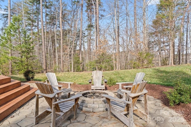 view of patio / terrace with a fire pit and a view of trees