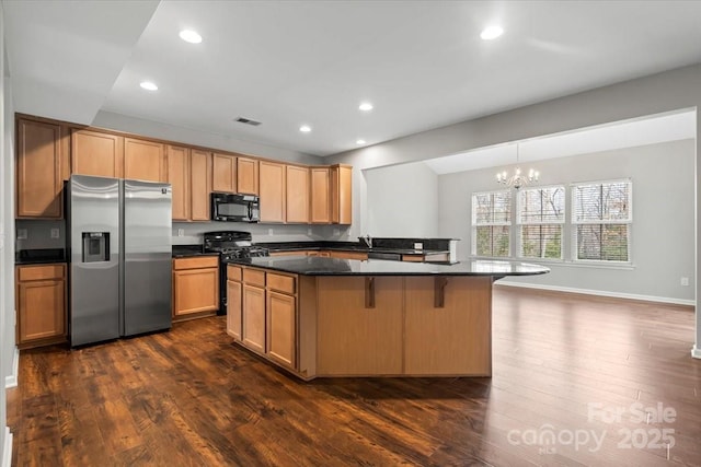 kitchen with dark countertops, black microwave, gas range, a notable chandelier, and stainless steel fridge