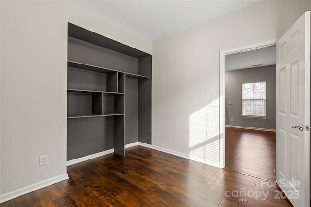 unfurnished bedroom with a closet, baseboards, and hardwood / wood-style flooring