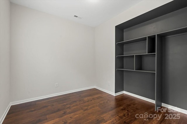 unfurnished bedroom featuring visible vents, baseboards, and wood finished floors