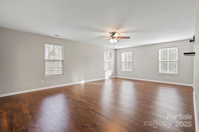 spare room featuring a wealth of natural light, dark wood-style flooring, and a ceiling fan