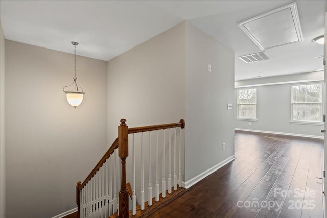 corridor with wood finished floors, visible vents, baseboards, attic access, and an upstairs landing