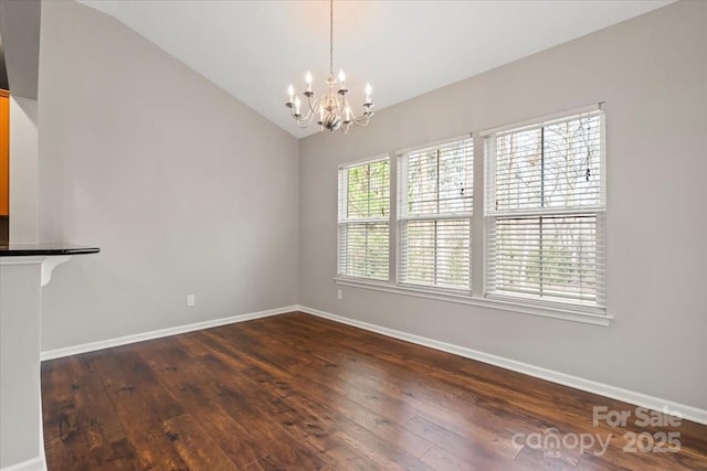 unfurnished dining area featuring lofted ceiling, a notable chandelier, dark wood-style floors, and baseboards