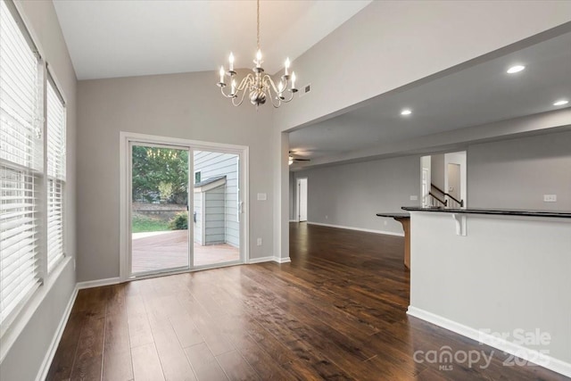 unfurnished dining area featuring dark wood-type flooring, lofted ceiling, recessed lighting, baseboards, and a chandelier