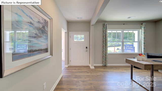 foyer entrance with visible vents, beamed ceiling, baseboards, and wood finished floors