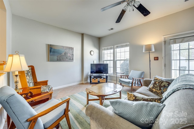 living room with light tile patterned floors, visible vents, baseboards, and a ceiling fan