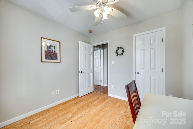 unfurnished office with baseboards, a ceiling fan, and light wood-style floors