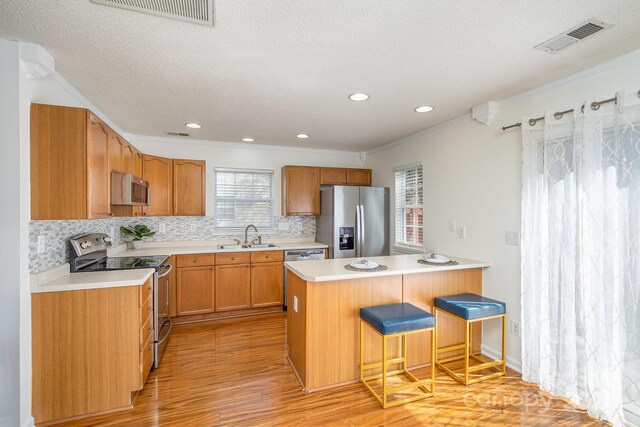 kitchen featuring visible vents, a peninsula, stainless steel appliances, and a sink