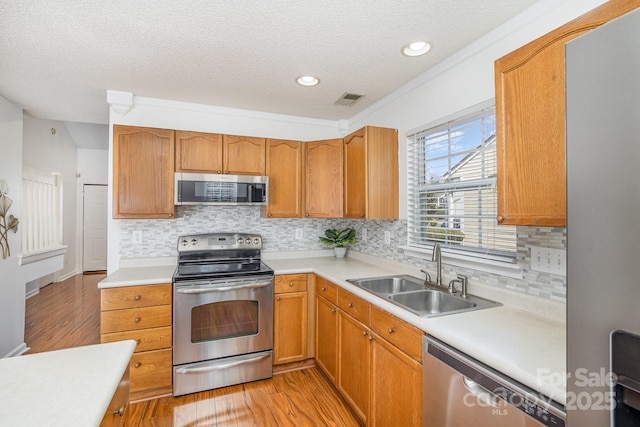 kitchen with visible vents, light wood-style flooring, a sink, appliances with stainless steel finishes, and light countertops