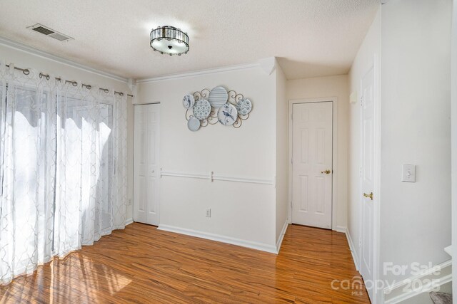 empty room featuring baseboards, wood finished floors, visible vents, and a textured ceiling