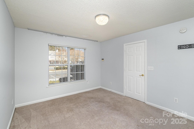 carpeted empty room with a textured ceiling and baseboards