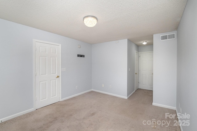 carpeted spare room featuring visible vents, baseboards, and a textured ceiling