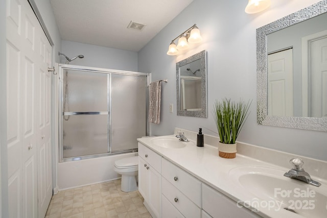 bathroom featuring double vanity, visible vents, shower / bath combination with glass door, and a sink