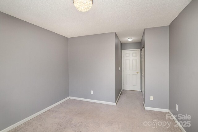 unfurnished room with a textured ceiling, baseboards, and carpet floors