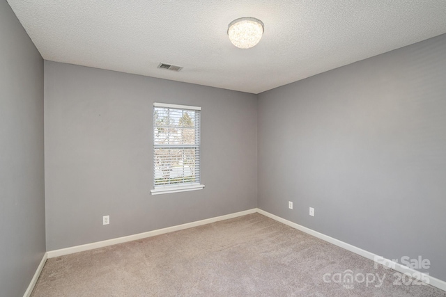 unfurnished room featuring visible vents, baseboards, a textured ceiling, and carpet flooring