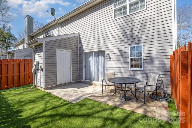 back of property featuring a patio area, a chimney, a yard, and fence