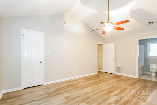 unfurnished bedroom featuring vaulted ceiling, light wood-style floors, visible vents, and ensuite bathroom