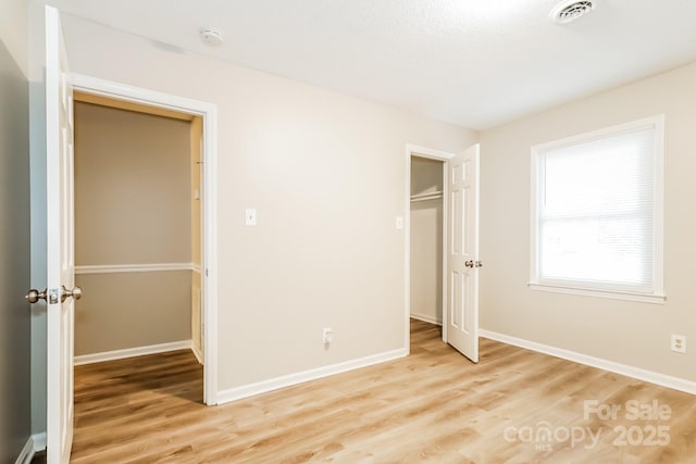 unfurnished bedroom with light wood-type flooring, visible vents, baseboards, and a closet