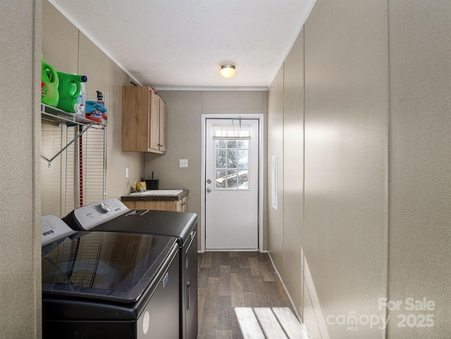 clothes washing area featuring a textured ceiling, dark wood-style floors, cabinet space, and washing machine and clothes dryer