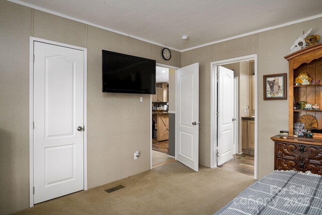 bedroom with visible vents, carpet flooring, connected bathroom, and ornamental molding