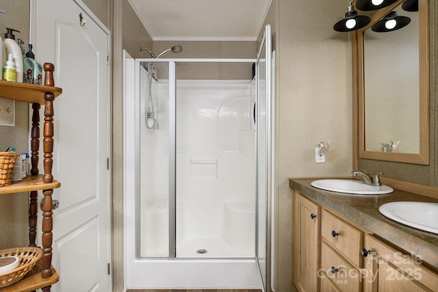 bathroom featuring double vanity, a stall shower, and a sink