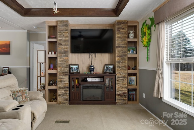 carpeted living room with visible vents, built in features, ornamental molding, a fireplace, and a raised ceiling