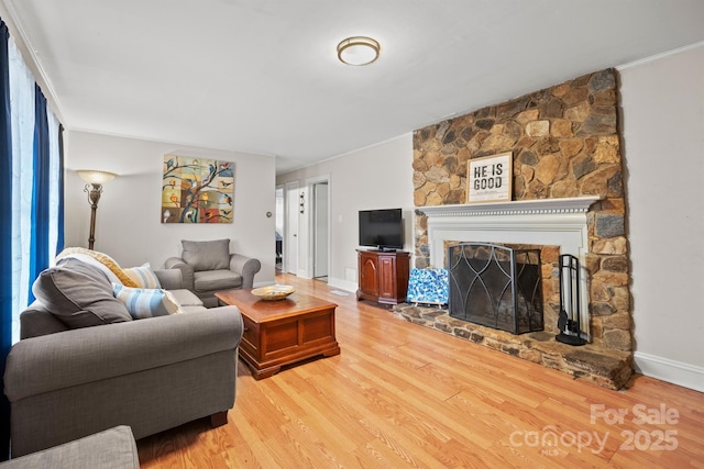 living area featuring baseboards, a fireplace, and light wood finished floors