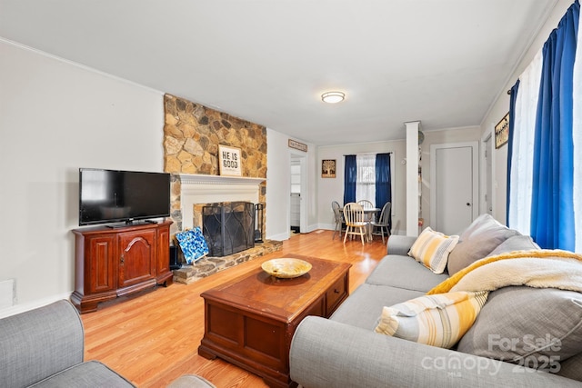 living room with a fireplace, baseboards, light wood-style floors, and ornamental molding