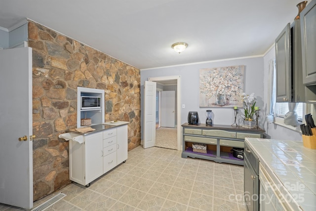 kitchen featuring tile countertops, light floors, and ornamental molding