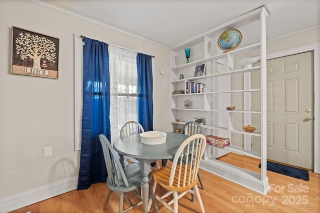 dining room with baseboards, wood finished floors, and crown molding