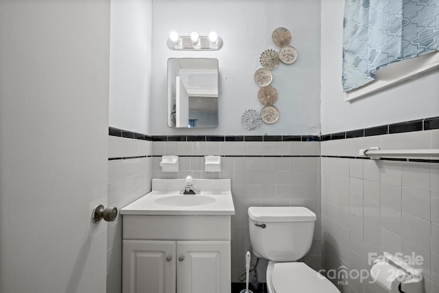 half bath with toilet, wainscoting, and vanity