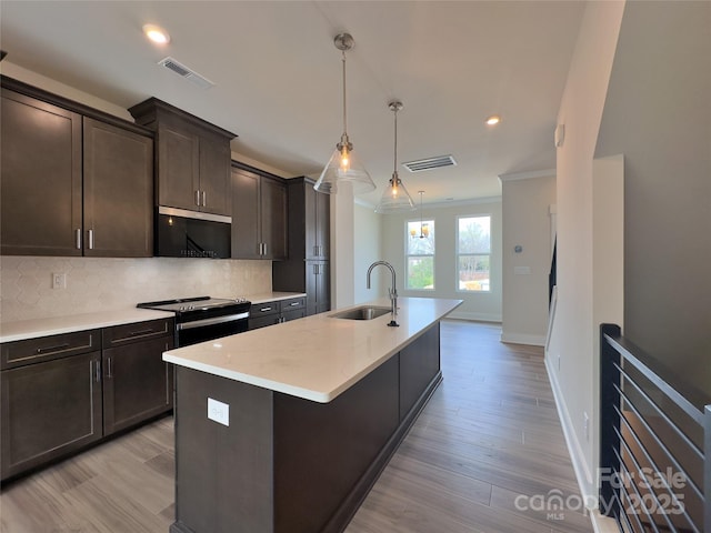 kitchen with a sink, range with electric stovetop, light countertops, decorative backsplash, and dark brown cabinets