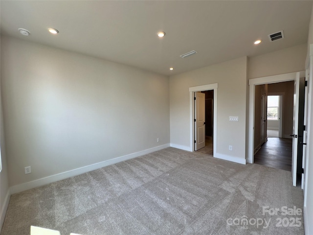 unfurnished bedroom featuring visible vents, a walk in closet, recessed lighting, carpet floors, and baseboards