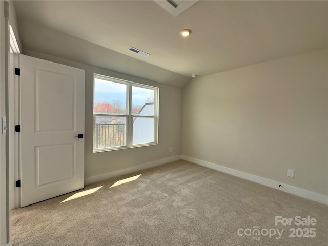 empty room with lofted ceiling, visible vents, baseboards, and carpet floors