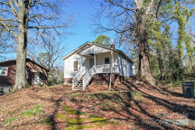 bungalow-style house featuring covered porch and a chimney